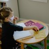 Girl reaching for stencils in a classroom while wearing a mask in El Paso, Texas